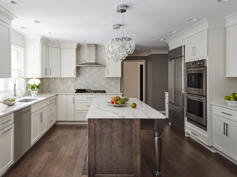 Large contemporary separate kitchen in Milwaukee with a single-bowl sink, shaker cabinets, white cabinets, quartz benchtops, metallic splashback, marble splashback, stainless steel appliances, dark hardwood floors, with island, brown floor and white benchtop.