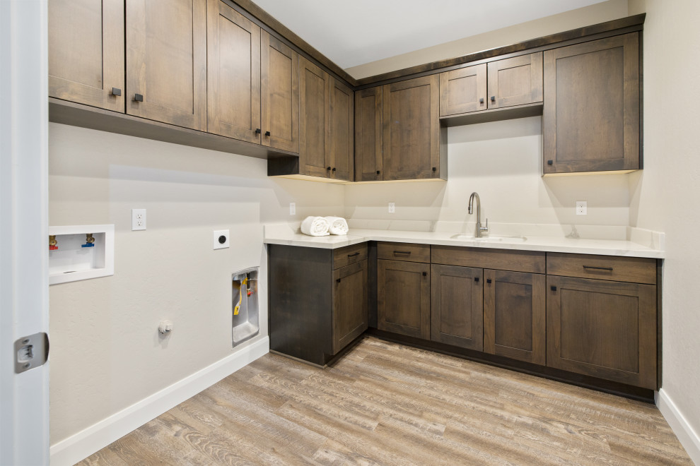 Inspiration for a mid-sized transitional dedicated laundry room in Other with an undermount sink, shaker cabinets, brown cabinets, quartz benchtops, white splashback, engineered quartz splashback, grey walls, vinyl floors, a side-by-side washer and dryer, brown floor and white benchtop.