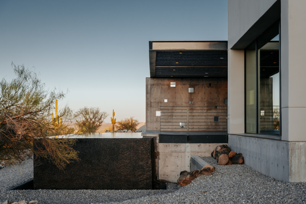 This is an example of a large modern front yard rectangular infinity pool in Phoenix with decomposed granite.