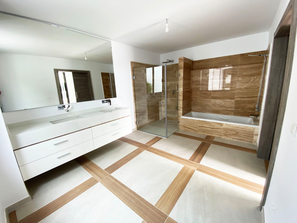 Idéer för stora funkis vitt en-suite badrum, med släta luckor, vita skåp, ett badkar i en alkov, en kantlös dusch, en vägghängd toalettstol, brun kakel, marmorkakel, vita väggar, klinkergolv i porslin, ett avlångt handfat, bänkskiva i kvarts, brunt golv och dusch med gångjärnsdörr