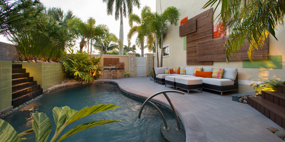 This is an example of a mid-sized contemporary custom-shaped pool in Miami with a water feature and tile.
