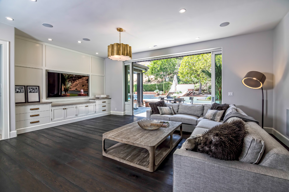 Photo of a mid-sized transitional open concept family room in Los Angeles with grey walls, dark hardwood floors, no fireplace, a concealed tv and brown floor.