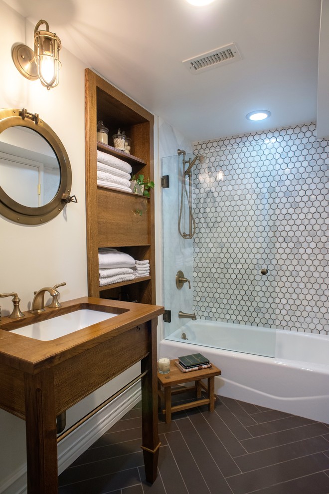 Transitional gray tile, white tile and stone tile porcelain tile and brown floor tub/shower combo photo with furniture-like cabinets, dark wood cabinets, beige walls, an undermount sink and wood countertops