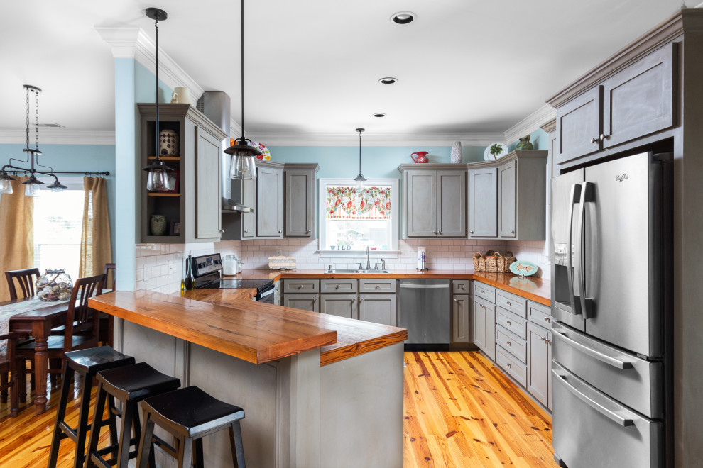 Inspiration for a mid-sized transitional u-shaped separate kitchen in Charleston with grey cabinets, wood benchtops, white splashback, stainless steel appliances, no island, a double-bowl sink, medium hardwood floors, brown floor and brown benchtop.