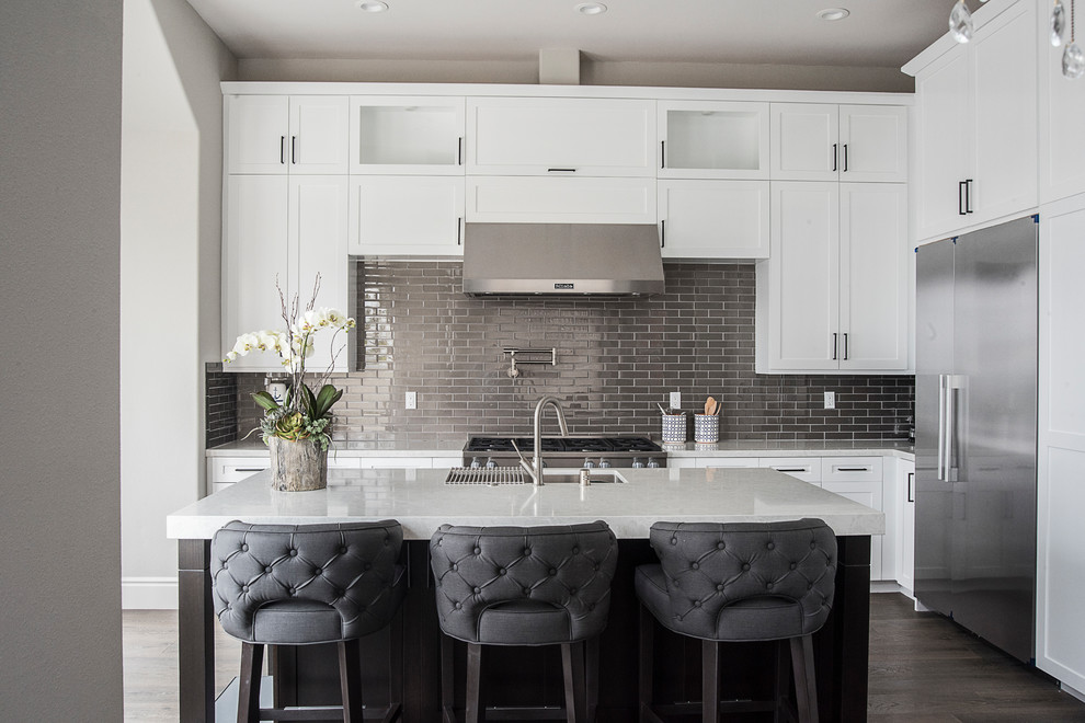 Design ideas for a mid-sized transitional l-shaped kitchen in Orange County with an undermount sink, shaker cabinets, white cabinets, quartz benchtops, stainless steel appliances, with island, white benchtop, metallic splashback, metal splashback and dark hardwood floors.
