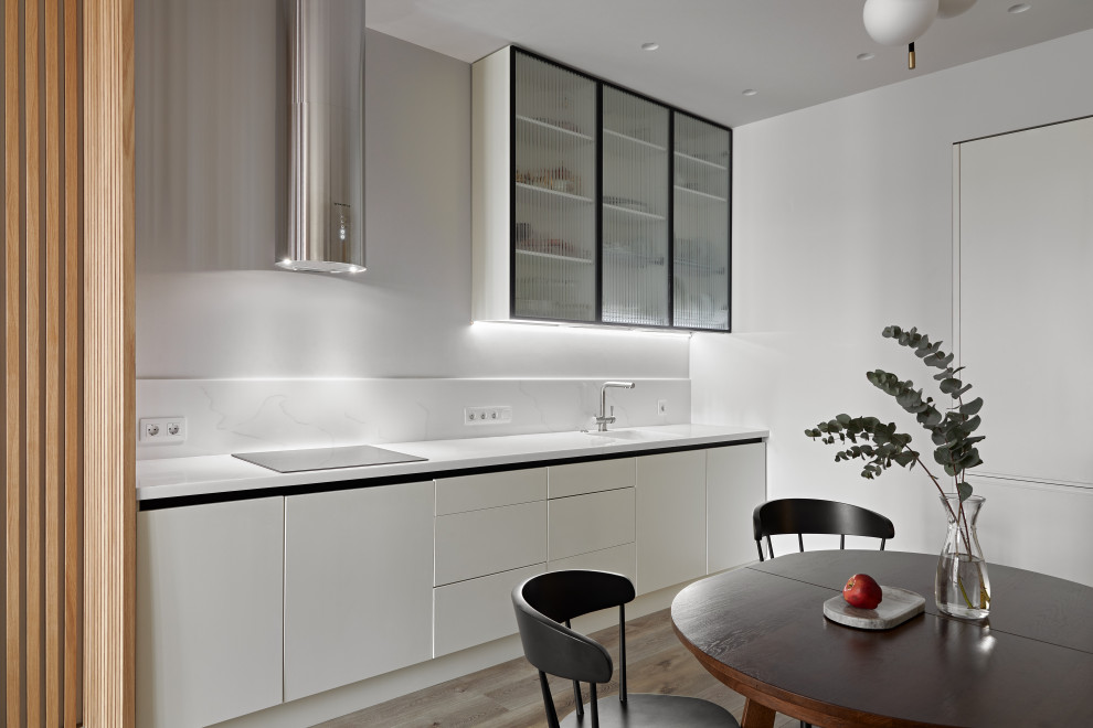 Bild på ett mellanstort funkis vit linjärt vitt kök och matrum, med släta luckor, vita skåp, bänkskiva i koppar, vitt stänkskydd, svarta vitvaror, mellanmörkt trägolv och brunt golv