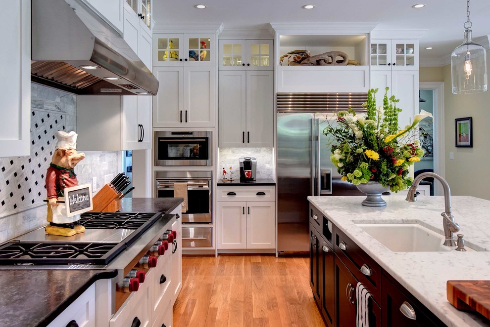 Transitional medium tone wood floor eat-in kitchen photo with an undermount sink, shaker cabinets, white cabinets, marble countertops, gray backsplash, subway tile backsplash, stainless steel appliances and an island