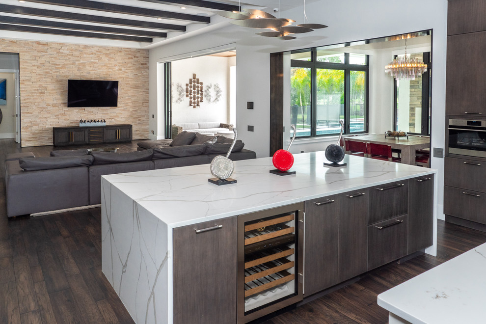 This is an example of a contemporary u-shaped kitchen in Tampa with flat-panel cabinets, dark wood cabinets, white splashback, stone slab splashback, stainless steel appliances, dark hardwood floors, multiple islands, brown floor and white benchtop.