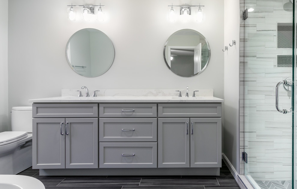Inspiration for a large contemporary master bathroom in DC Metro with recessed-panel cabinets, grey cabinets, a freestanding tub, a corner shower, a two-piece toilet, grey walls, porcelain floors, an undermount sink, grey floor, a hinged shower door and white benchtops.