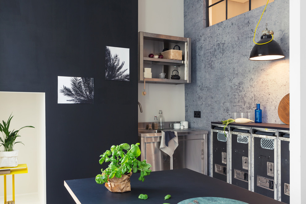 Photo of a small industrial kitchen in Berlin with an integrated sink, black cabinets and grey splashback.