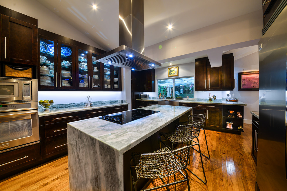 Large contemporary u-shaped eat-in kitchen in Miami with shaker cabinets, dark wood cabinets, marble benchtops, stainless steel appliances, medium hardwood floors, with island and a farmhouse sink.