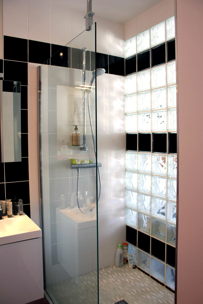 This is an example of a mid-sized traditional master bathroom in Paris with flat-panel cabinets, white cabinets, a curbless shower, a wall-mount toilet, black and white tile, glass tile, orange walls, linoleum floors, a trough sink, limestone benchtops, orange floor, an open shower and blue benchtops.