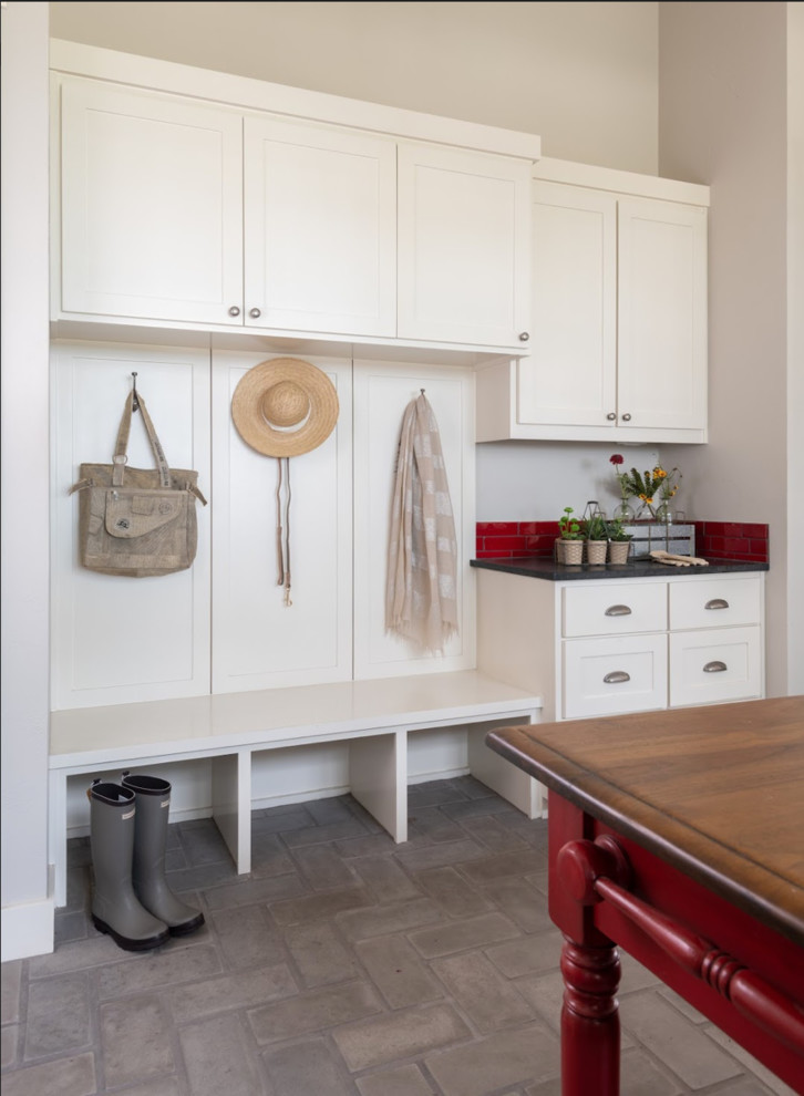 Inspiration for a transitional mudroom in Austin with beige walls and brick floors.