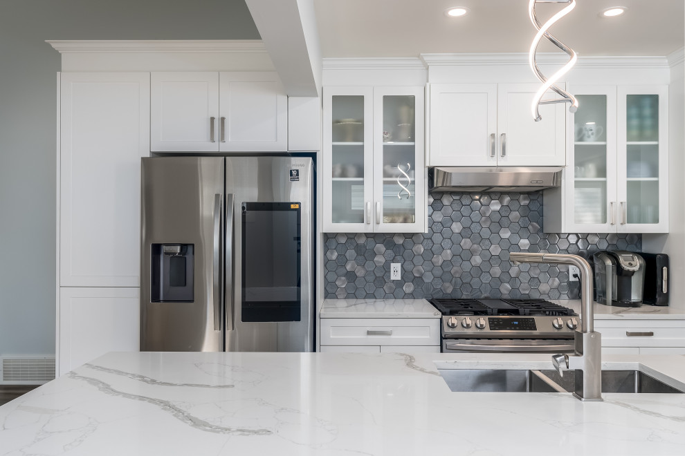 Kitchen - transitional kitchen idea in Edmonton with shaker cabinets, white cabinets, quartzite countertops, gray backsplash, cement tile backsplash, stainless steel appliances, an island and white countertops