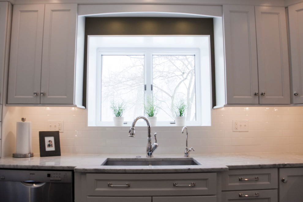 Example of a transitional kitchen design with white cabinets and marble countertops