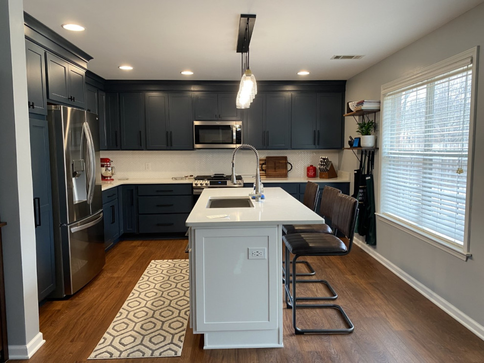 Enclosed kitchen - mid-sized transitional u-shaped brown floor enclosed kitchen idea with an undermount sink, shaker cabinets, blue cabinets, quartz countertops, white backsplash, stainless steel appliances, an island and white countertops