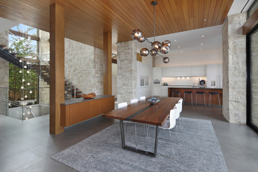 Contemporary open plan dining in San Diego with white walls, grey floor and wood.