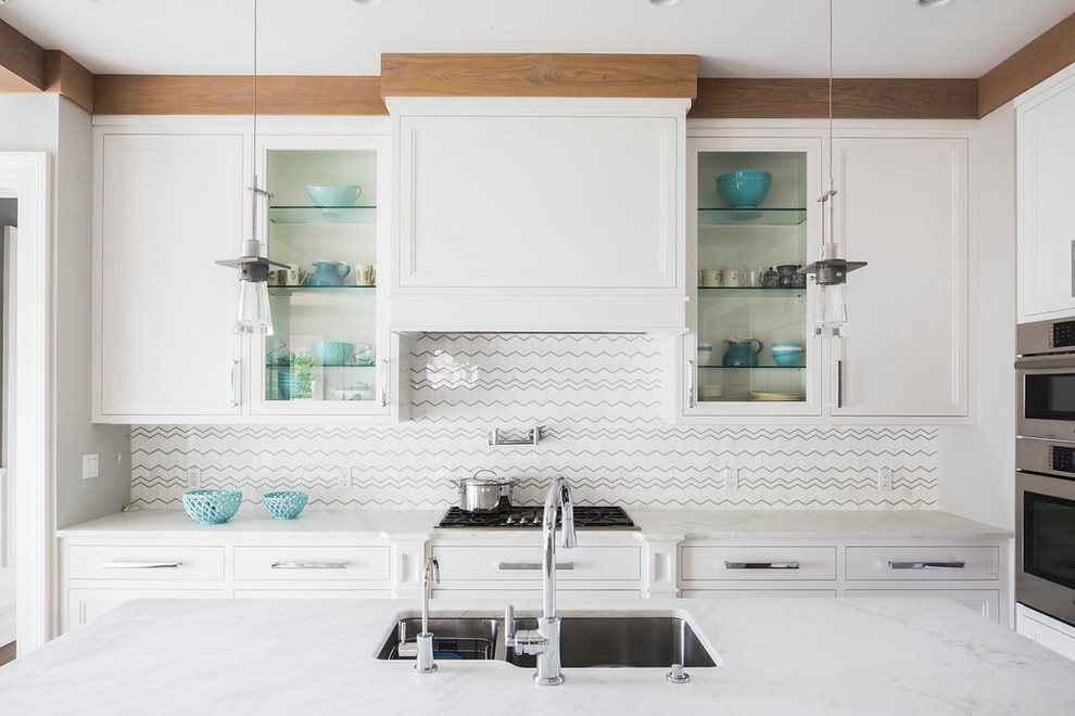 Inspiration for a large transitional medium tone wood floor eat-in kitchen remodel in New York with an undermount sink, shaker cabinets, white cabinets, marble countertops, white backsplash, mosaic tile backsplash, stainless steel appliances and an island