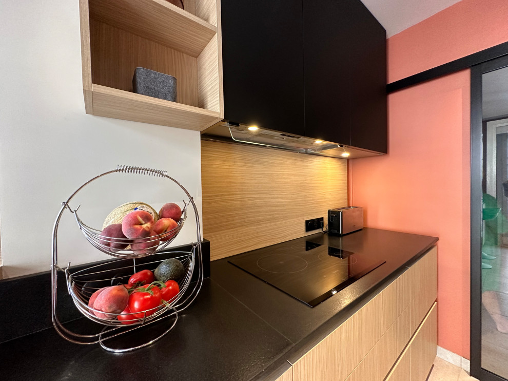 Medium sized modern galley enclosed kitchen in Le Havre with an integrated sink, beaded cabinets, light wood cabinets, granite worktops, wood splashback, black appliances, ceramic flooring, no island, beige floors and black worktops.