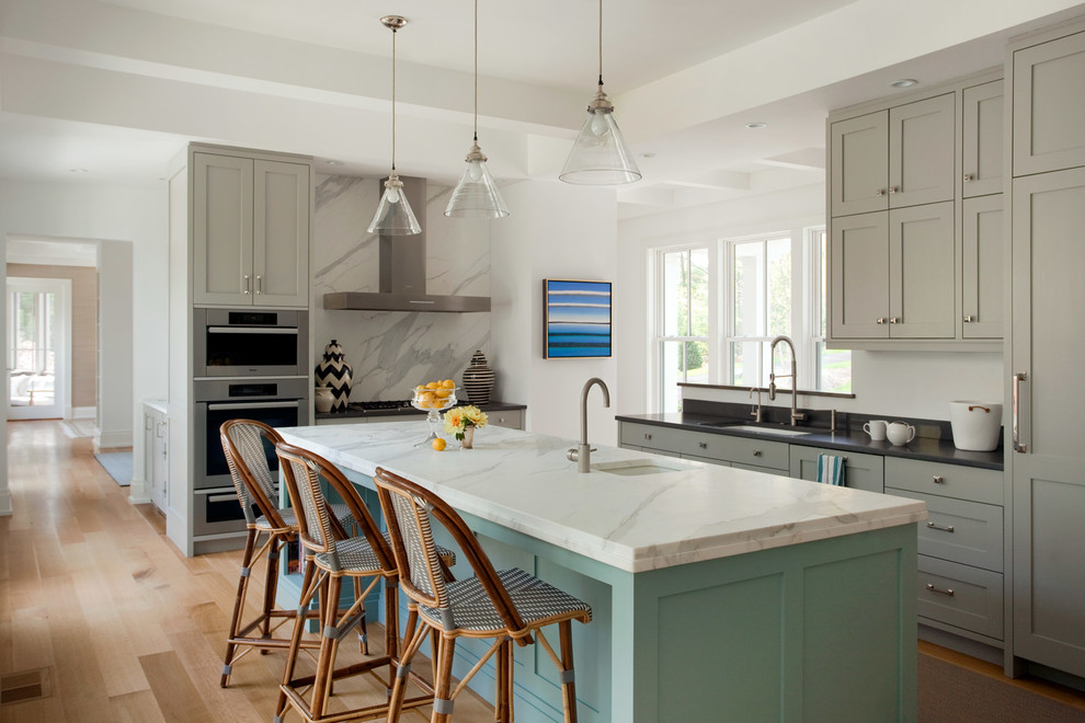This is an example of a beach style l-shaped kitchen in Boston with an undermount sink, shaker cabinets, turquoise cabinets, multi-coloured splashback, panelled appliances, medium hardwood floors, with island and brown floor.