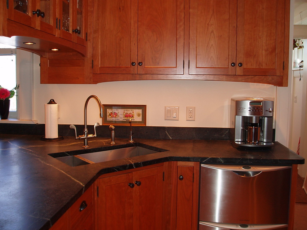 This is an example of a traditional u-shaped eat-in kitchen in Cedar Rapids with an undermount sink, shaker cabinets, medium wood cabinets, soapstone benchtops, black splashback, stone slab splashback, stainless steel appliances, linoleum floors, a peninsula and yellow floor.
