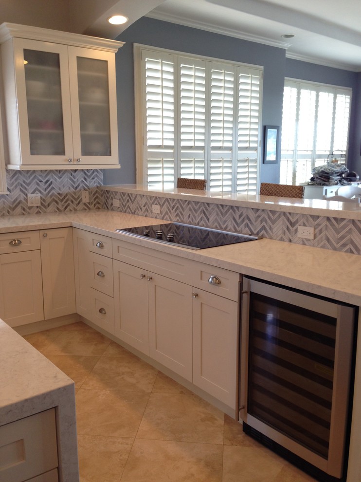 Inspiration for a mid-sized traditional u-shaped eat-in kitchen in Hawaii with a farmhouse sink, shaker cabinets, white cabinets, solid surface benchtops, grey splashback, mosaic tile splashback, stainless steel appliances, ceramic floors and with island.