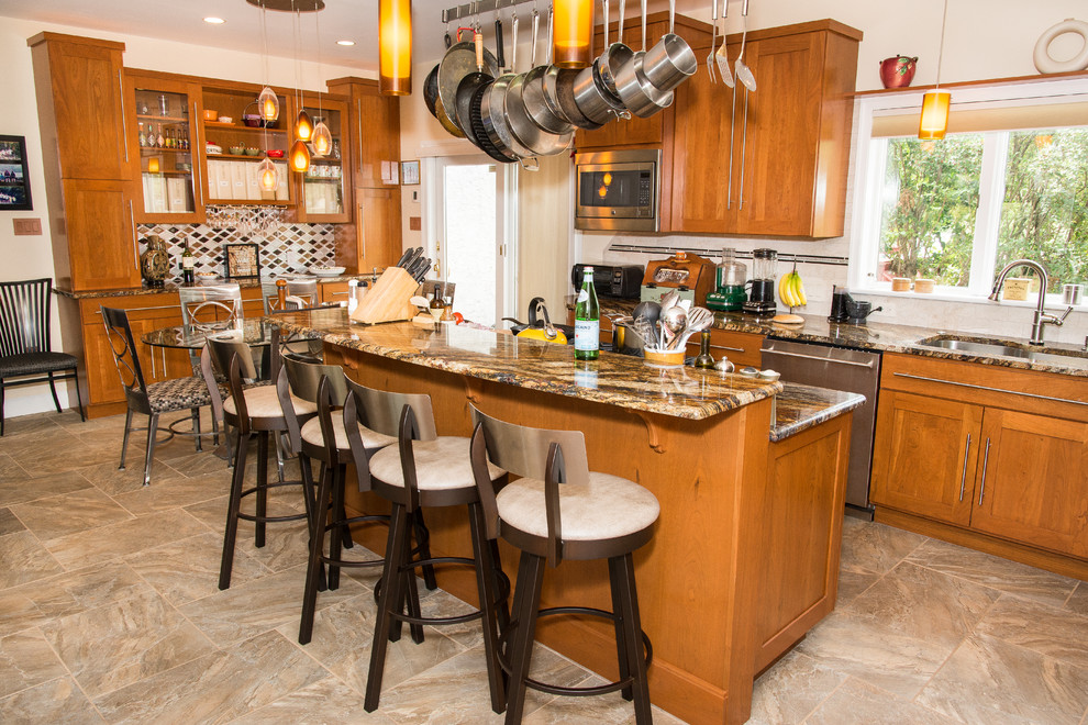 Photo of an expansive contemporary l-shaped eat-in kitchen in Philadelphia with a single-bowl sink, shaker cabinets, orange cabinets, granite benchtops, beige splashback, stone tile splashback, stainless steel appliances, porcelain floors, with island and brown floor.