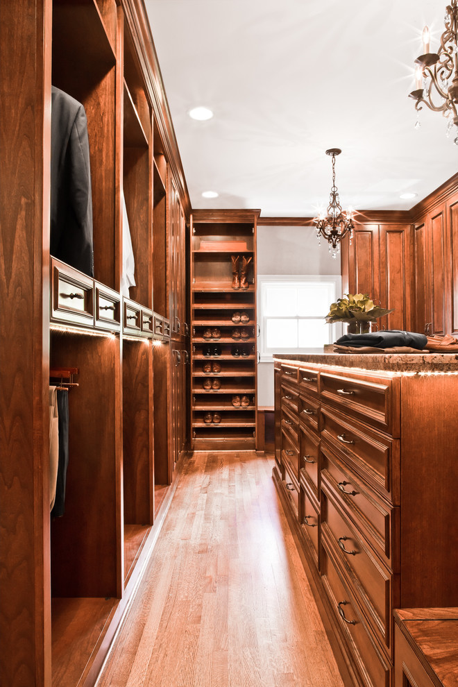 Design ideas for a large traditional gender-neutral walk-in wardrobe in Houston with raised-panel cabinets, medium wood cabinets and medium hardwood floors.