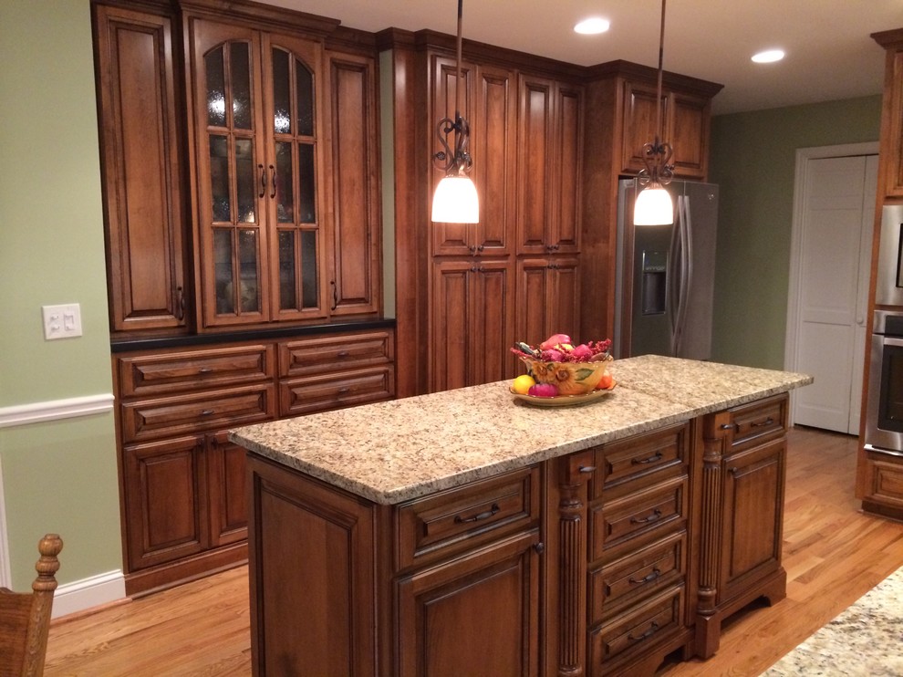 Inspiration for a mid-sized traditional l-shaped eat-in kitchen in Atlanta with a double-bowl sink, raised-panel cabinets, dark wood cabinets, granite benchtops, beige splashback, stainless steel appliances, medium hardwood floors and with island.