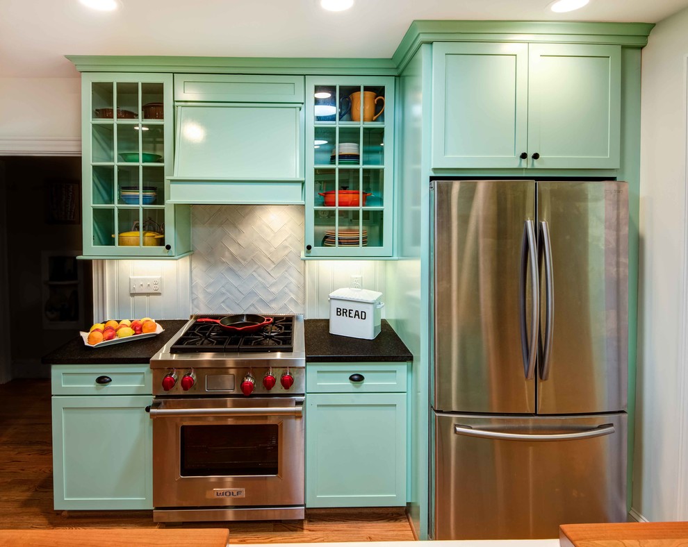 Inspiration for a small midcentury galley eat-in kitchen in Raleigh with a farmhouse sink, shaker cabinets, turquoise cabinets, granite benchtops, white splashback, porcelain splashback, stainless steel appliances, medium hardwood floors, with island, brown floor and black benchtop.