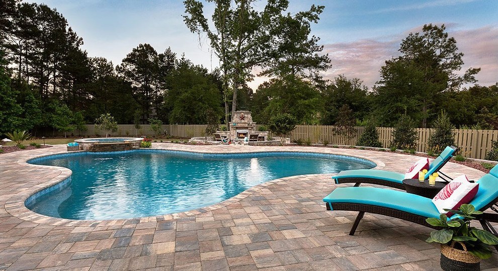 Inspiration for a mid-sized traditional backyard custom-shaped pool in Tampa with a hot tub and stamped concrete.