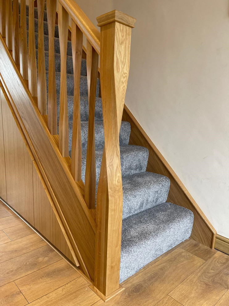 Diseño de escalera en L contemporánea de tamaño medio con escalones enmoquetados, contrahuellas enmoquetadas y barandilla de madera