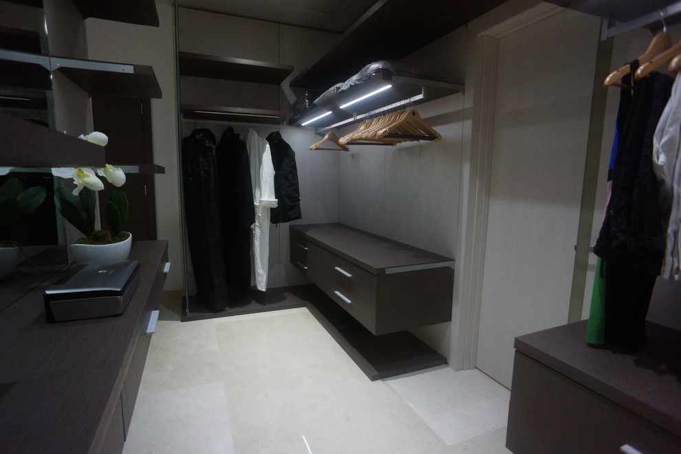 Photo of a large modern gender-neutral walk-in wardrobe in Miami with flat-panel cabinets, dark wood cabinets and porcelain floors.