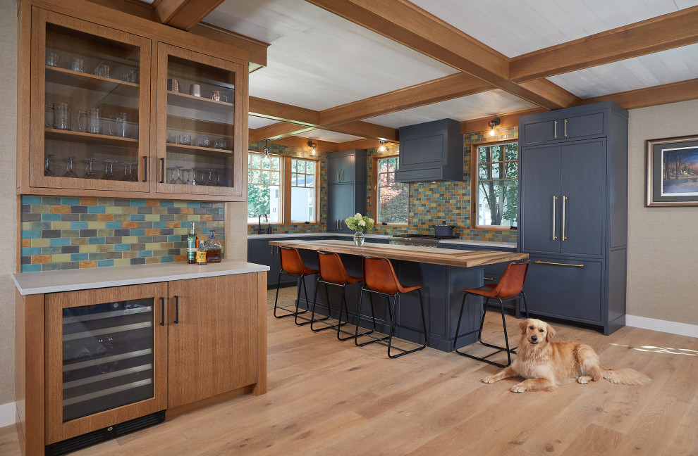 Eat-in kitchen - large craftsman l-shaped medium tone wood floor and coffered ceiling eat-in kitchen idea in Grand Rapids with an undermount sink, shaker cabinets, blue cabinets, wood countertops, multicolored backsplash, subway tile backsplash, paneled appliances and an island