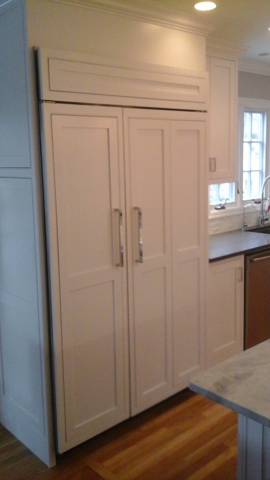 Inspiration for a mid-sized transitional l-shaped light wood floor eat-in kitchen remodel in Newark with a double-bowl sink, shaker cabinets, white cabinets, solid surface countertops, multicolored backsplash, stone tile backsplash, stainless steel appliances and an island