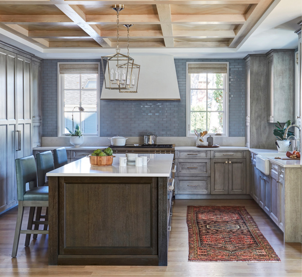 Kitchen - transitional u-shaped light wood floor, beige floor, exposed beam and wood ceiling kitchen idea in Other with a farmhouse sink, recessed-panel cabinets, gray cabinets, gray backsplash, glass tile backsplash, stainless steel appliances, an island and white countertops