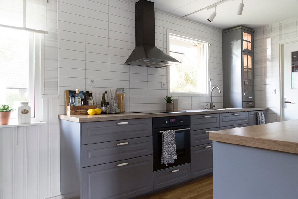 Inspiration for a mid-sized country eat-in kitchen in Malmo with a double-bowl sink, grey cabinets, laminate benchtops, medium hardwood floors and with island.