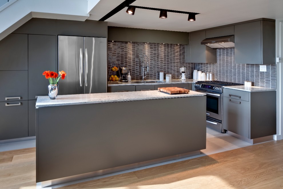 This is an example of a mid-sized modern l-shaped open plan kitchen in Toronto with granite benchtops, flat-panel cabinets, grey cabinets, grey splashback, stainless steel appliances, an undermount sink, ceramic splashback, porcelain floors and with island.