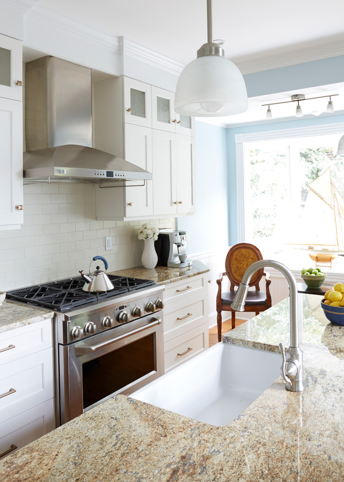 Inspiration for a transitional medium tone wood floor eat-in kitchen remodel in DC Metro with a farmhouse sink, recessed-panel cabinets, white cabinets, granite countertops, white backsplash, subway tile backsplash, stainless steel appliances and an island