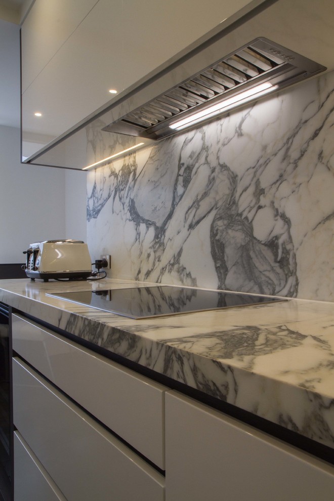 Photo of a small modern galley separate kitchen in Melbourne with flat-panel cabinets, white cabinets, marble benchtops, stone slab splashback and no island.