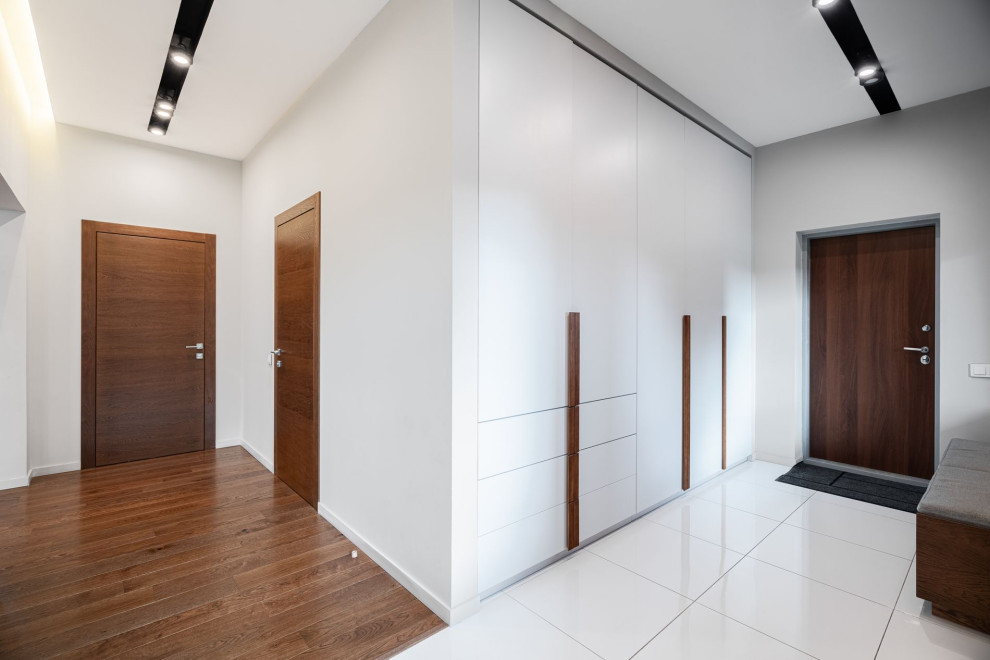 Immagine di una porta d'ingresso design di medie dimensioni con pareti bianche, pavimento in gres porcellanato e pavimento bianco