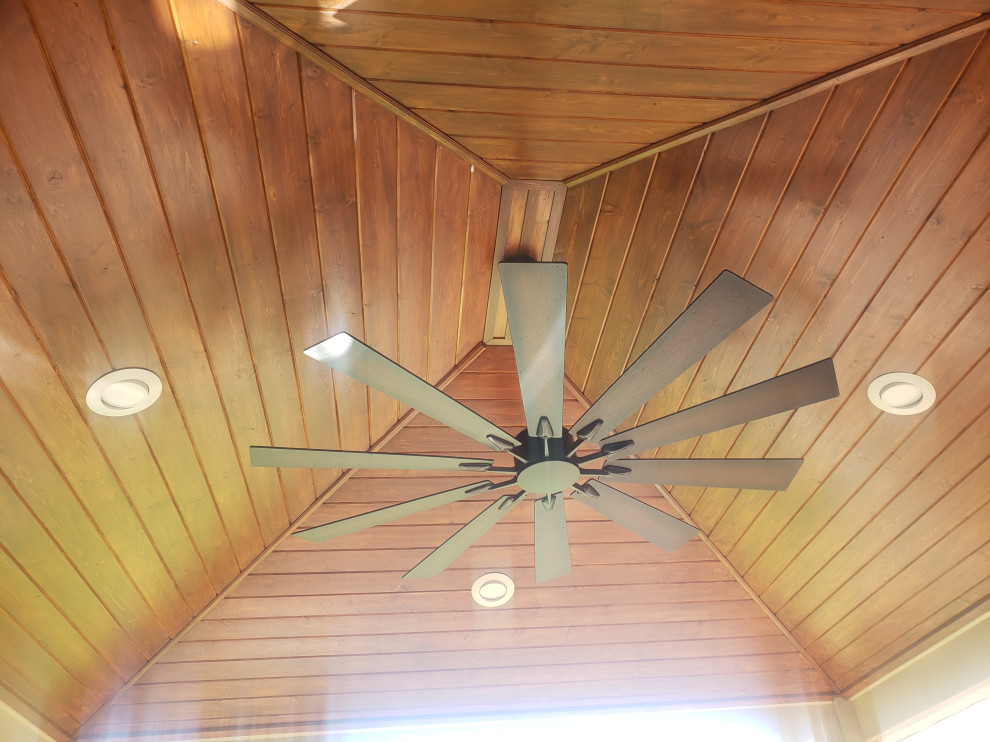 Example of a trendy ground level metal railing deck design with a roof extension