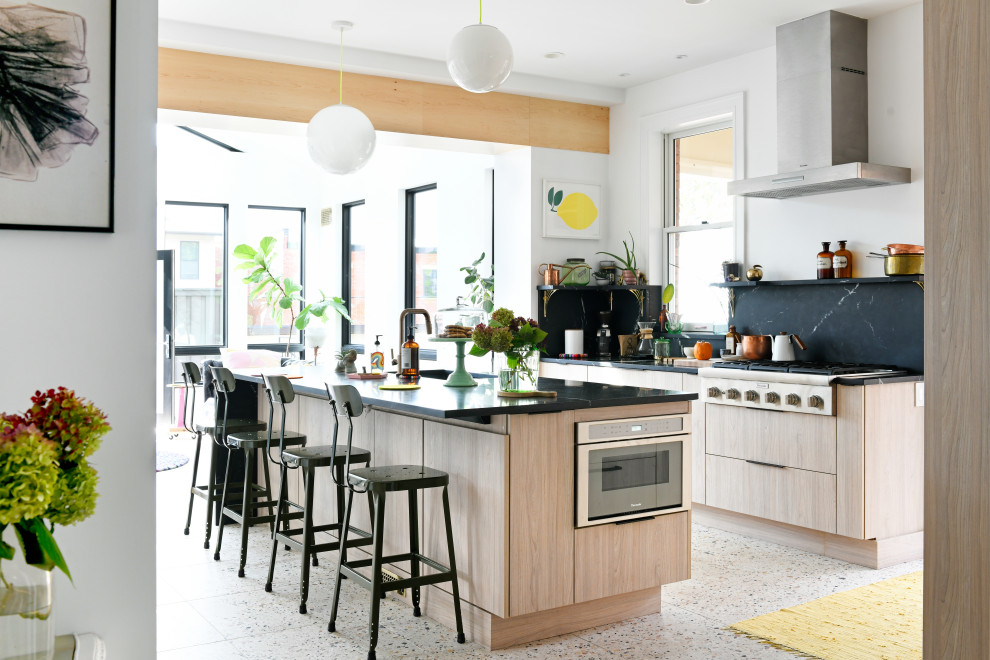 Design ideas for a midcentury open plan kitchen in Other with flat-panel cabinets, light wood cabinets, marble benchtops, black splashback, marble splashback, stainless steel appliances, terrazzo floors and with island.