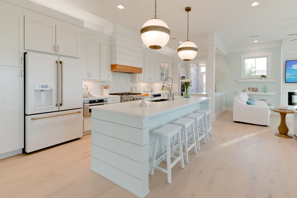Design ideas for a large nautical galley open plan kitchen in Other with a single-bowl sink, shaker cabinets, white cabinets, engineered stone countertops, green splashback, glass tiled splashback, white appliances, light hardwood flooring, multiple islands, grey floors and white worktops.