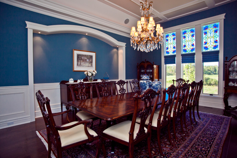 This is an example of a large traditional separate dining room in Toronto with blue walls, dark hardwood floors, no fireplace and brown floor.