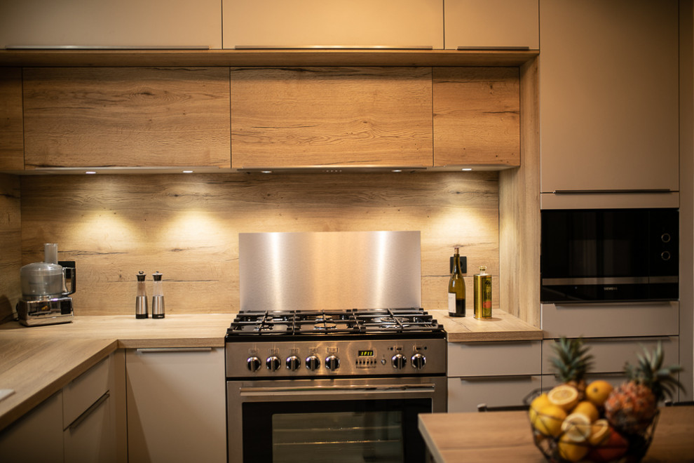 This is an example of a large contemporary l-shaped separate kitchen in Lyon with a single-bowl sink, flat-panel cabinets, beige cabinets, laminate benchtops, metallic splashback, timber splashback, stainless steel appliances, ceramic floors, no island and beige benchtop.