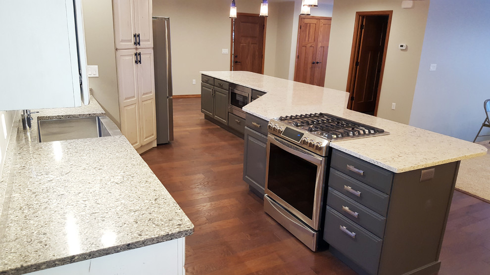 Example of a large transitional galley medium tone wood floor open concept kitchen design with a farmhouse sink, raised-panel cabinets, white cabinets, quartz countertops, stainless steel appliances and an island