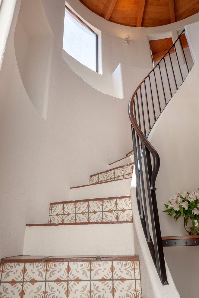 Inspiration for a mid-sized mediterranean tile curved staircase in Los Angeles with metal railing.