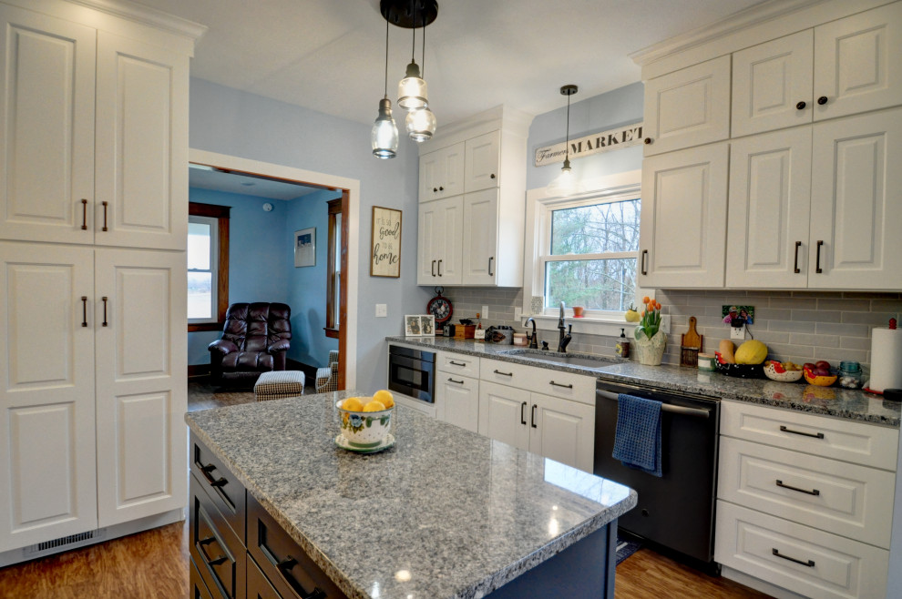 Exempel på ett mellanstort klassiskt flerfärgad flerfärgat kök, med en undermonterad diskho, luckor med upphöjd panel, vita skåp, granitbänkskiva, grått stänkskydd, stänkskydd i tunnelbanekakel, rostfria vitvaror, vinylgolv, en köksö och brunt golv
