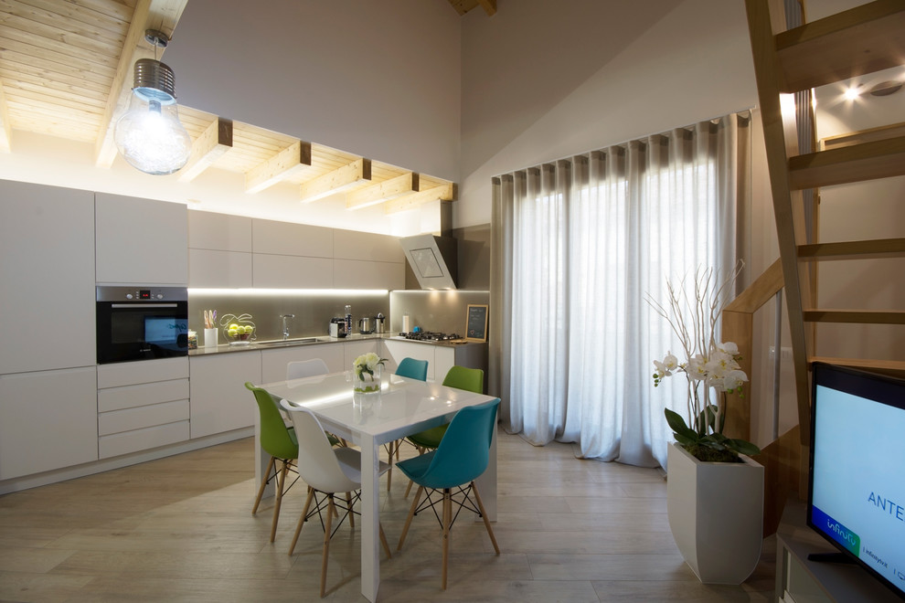 This is an example of a mid-sized modern l-shaped eat-in kitchen in Other with flat-panel cabinets, white cabinets, grey splashback, stainless steel appliances, porcelain floors and no island.